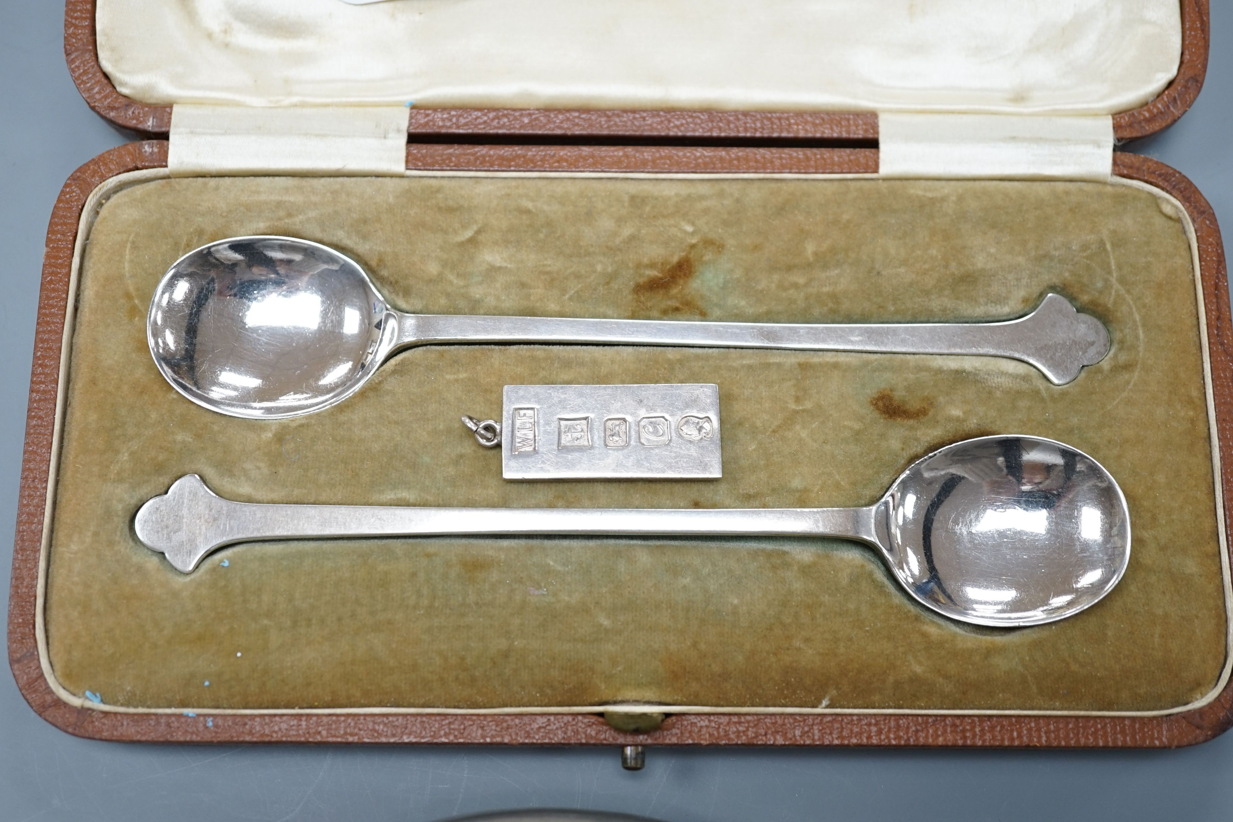 A cased pair of George V silver preserve spoons, Sheffield 1911, 36 grams, an ingot pendant, 15 grams and a pewter pocket flask